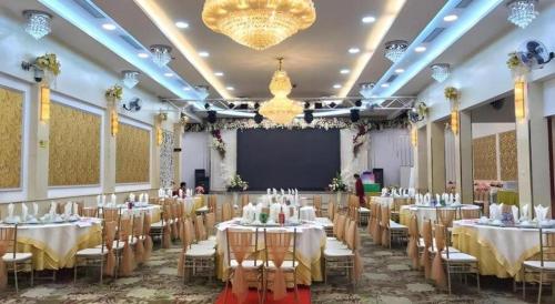 a banquet hall with tables and chairs and a screen at Hacinco Hotel in Hanoi
