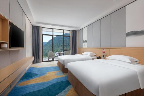 une chambre d'hôtel avec trois lits et une télévision dans l'établissement Ramada Encore by Wyndham Enshi Huaxi Valley, à Jianshi