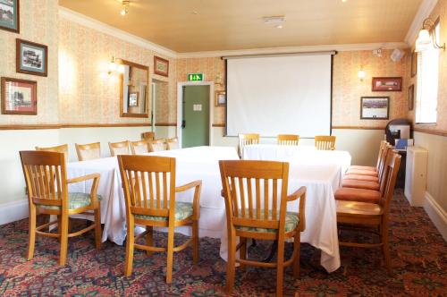 a conference room with a table and chairs and a screen at Radstock Hotel near Bath in Radstock