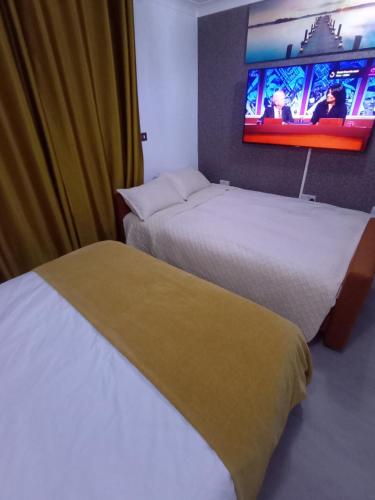 two beds in a hotel room with a tv on the wall at Bavelle Bilston Urban Village in Bilston