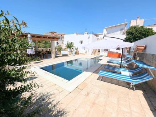 LucugnanoにあるBoutique Heritage Home and Loft with Pool & Gardenのスイミングプール(青い椅子、パラソル付)