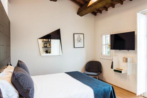a bedroom with a bed and a tv and a chair at Hotel Milu Florence in Florence