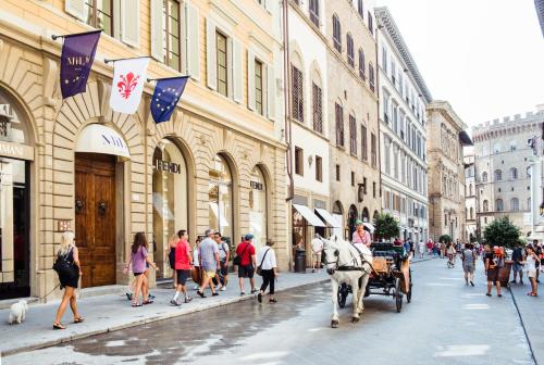 a horse drawn carriage on a city street with people at Hotel Milu Florence in Florence
