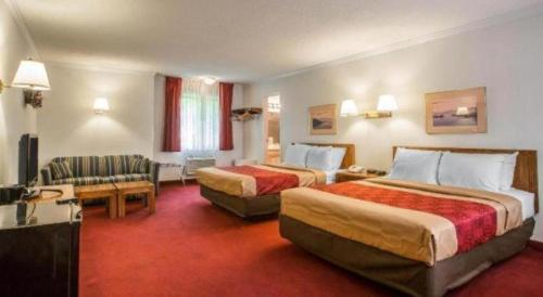 una camera d'albergo con due letti e un divano di Baymont by Wyndham Lake George a Lake George