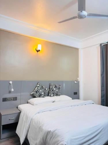 a bedroom with a bed with white sheets and a ceiling at The G Ten Holiday Inn in Hulhumale