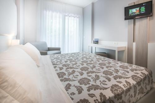 a bedroom with a bed and a chair and a desk at Hotel Bologna in Lignano Sabbiadoro