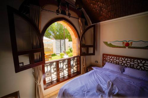 a bedroom with a bed and an open window at Osman Authentic Dome House Garden Retreat in Luxor