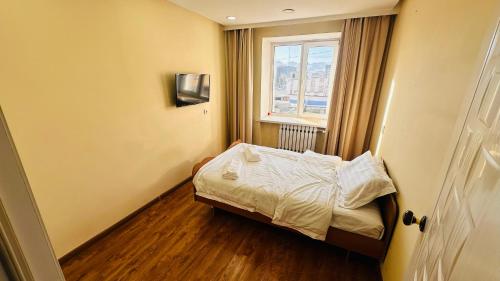 ein kleines Schlafzimmer mit einem Bett und einem Fenster in der Unterkunft Cozy apartment in downtown Ulgii in Ölgii