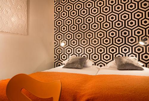 a bedroom with a bed with an orange blanket and a wall at Evora Inn in Évora