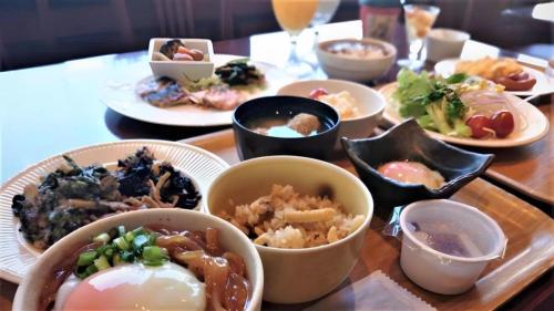 a table with plates of food and bowls of food at Hotel Harvest In Yonago in Yonago