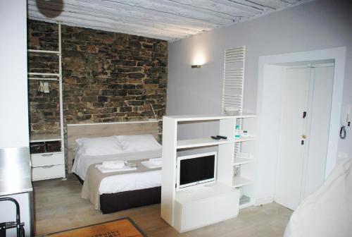 a bedroom with a bed and a tv and a brick wall at Lakeside Studio in Como
