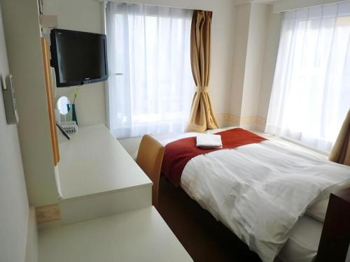 a small bedroom with a bed and a television at Hotel Shimbashi Sambankan in Tokyo