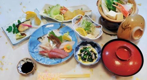 四万十市にあるAKISAWA HOTELのテーブルの上に並んだ一群の食べ物の皿
