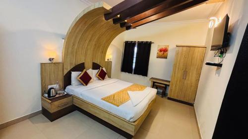a bedroom with a large bed with a wooden headboard at VR Residency in Ooty