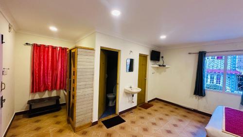 a bathroom with a toilet and a red curtain at VR Residency in Ooty