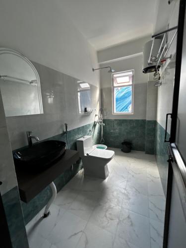 a bathroom with a black sink and a toilet at Norkyi Homestay in Tawang