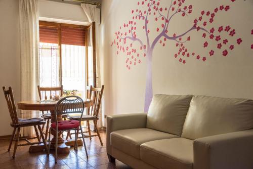 - un salon avec un canapé et un arbre sur le mur dans l'établissement Sa Mama e Su Sole, à Alghero