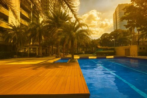 a swimming pool with palm trees next to a building at La Verti Residences Unit 1420 I Skyline Views & Luxe Stay Near MOA in Manila