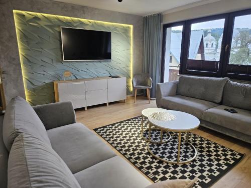 a living room with a couch and a tv at GOLD apartamenty & spa in Szczawnica