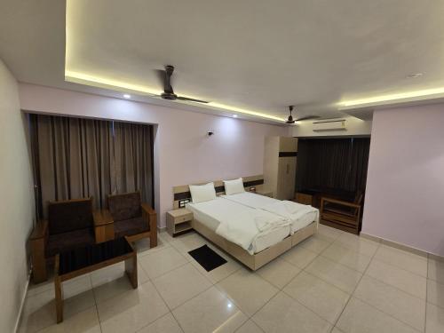 a bedroom with a bed and a couch and a chair at Krishnavasyam lodging in Uppinangadi