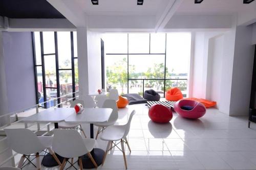 a dining room with white tables and red chairs at Chic-Chidkong Boutique Hotel in Nakhon Phanom