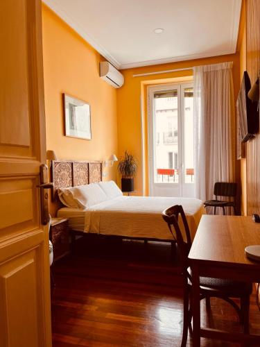 a bedroom with a bed and a table and a window at La casa de la escritora in Madrid