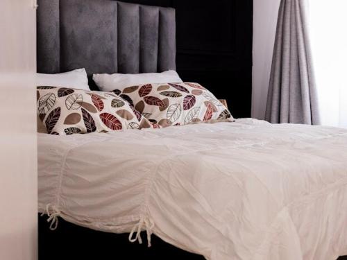een bed met witte lakens en kussens erop bij Bright and airy Harare CBD flat in Harare