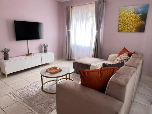 een woonkamer met een bank en een tv bij Bright and airy Harare CBD flat in Harare
