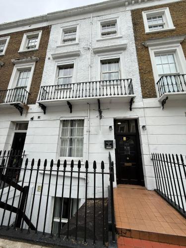 a white house with a black door and a fence at Oban Victoria Hotel in London