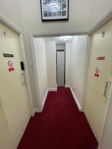 a hallway with a red carpet and signs on the walls at Oban Victoria Hotel in London
