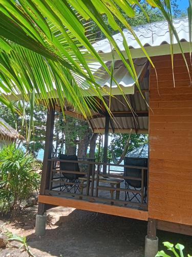 a patio with a table and chairs under a roof at Sunset Beach Bungalow Koh Pu in Ko Jum