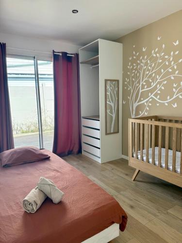 a bedroom with a crib and a tree mural at Maison Familiale plain pied à 2km de la mer in Trignac