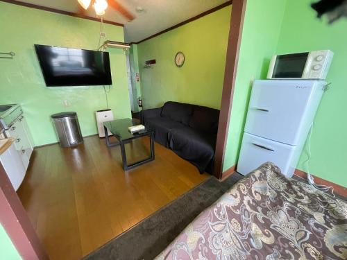 a small living room with a couch and a refrigerator at Guest House Koza Gate2 in Okinawa City