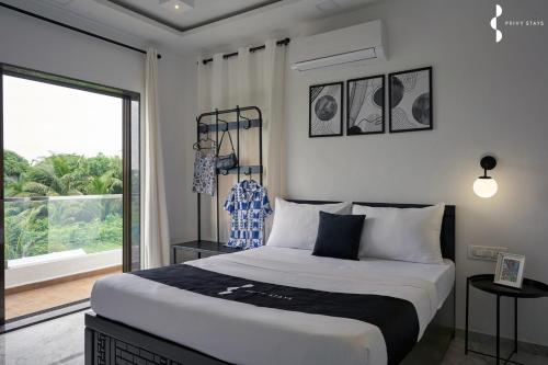 een slaapkamer met een groot bed en een groot raam bij Privy Stays- Cavo Villa, Alibag in Mān