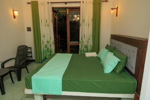 a bedroom with a bed with green sheets and a window at Wind Hill Villa - Weligama in Weligama