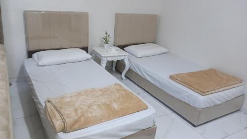 two beds in a white room with a table at سوما للشقق المفروشه Soma apt in Al Madinah