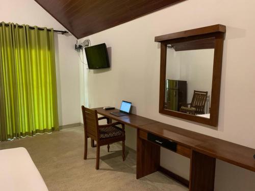 Habitación con escritorio, ordenador portátil y espejo. en The Royal Lake Cabanas, en Anuradhapura