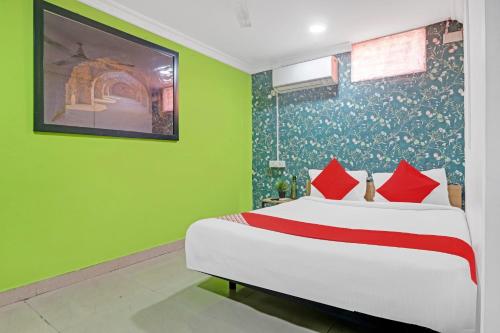 1 dormitorio con 1 cama con paredes verdes y almohadas rojas en Hotel O New Lakeview Palace, en Hyderabad