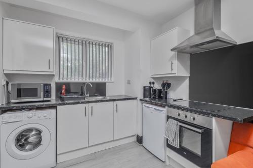 une cuisine avec des armoires blanches et une laveuse et une sécheuse dans l'établissement Sheaf 2 Sheldon 2BR Stay Sleeps 4 & Superfast Wi-Fi, à Sheldon