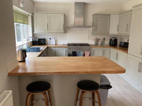 a kitchen with white cabinets and a wooden counter top at Large 4 bed detached house with parking in Newark-on-Trent