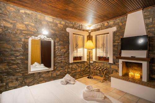 a bedroom with a stone wall with a bed and a fireplace at Elia Guesthouse Chaidemeni in Tríkala