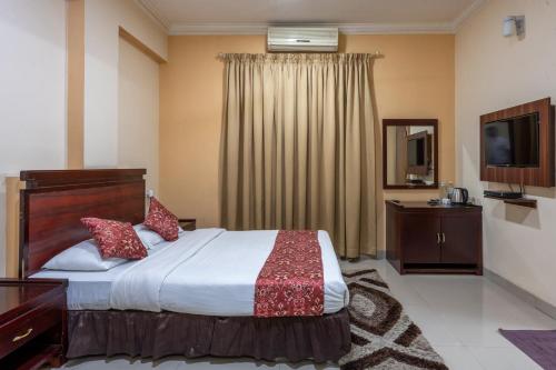 una camera d'albergo con un letto e una televisione di Tea Pavilion a Bangalore