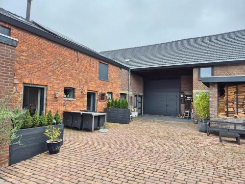 a brick building with a courtyard with a table and benches at Gastenverblijf Oesj in Eijsden