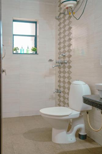 a bathroom with a toilet and a shower and a sink at Sukoon by Second Homes in Candolim