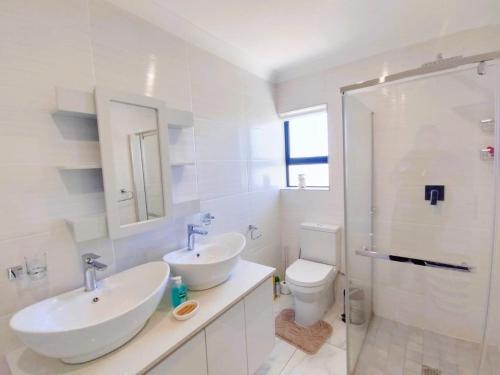 a white bathroom with two sinks and a toilet at Greenview Haven in Stompneusbaai