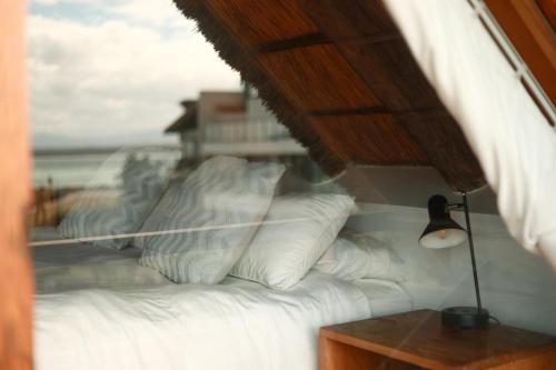 a bedroom with a bed with white pillows and a window at Dreamland Beach House & Studios at Supertubes in Jeffreys Bay