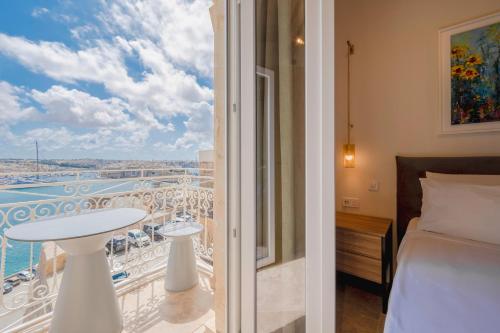 a bedroom with a bed and a balcony with a view at V60 Valletta in Valletta