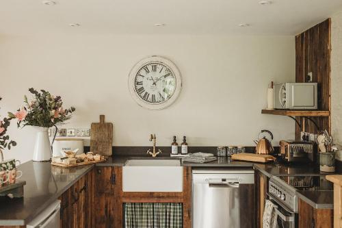a kitchen with a clock on the wall above a sink at Ty Mawr, The Old School Holiday Homes in Llanwrtyd Wells