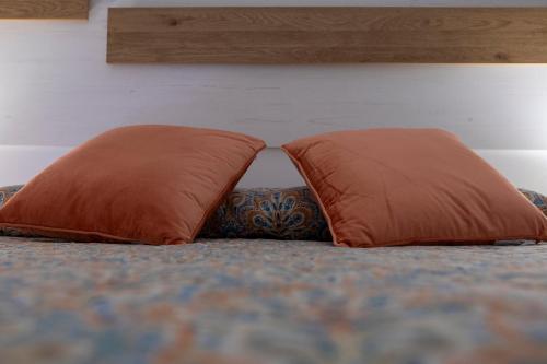 zwei orangefarbene Kissen auf einem Bett in der Unterkunft Vivienda rural La Puentezuela in Grazalema