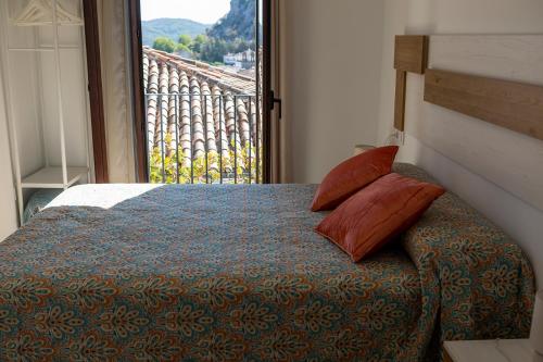 Schlafzimmer mit einem Bett und Blick auf einen Balkon in der Unterkunft Vivienda rural La Puentezuela in Grazalema